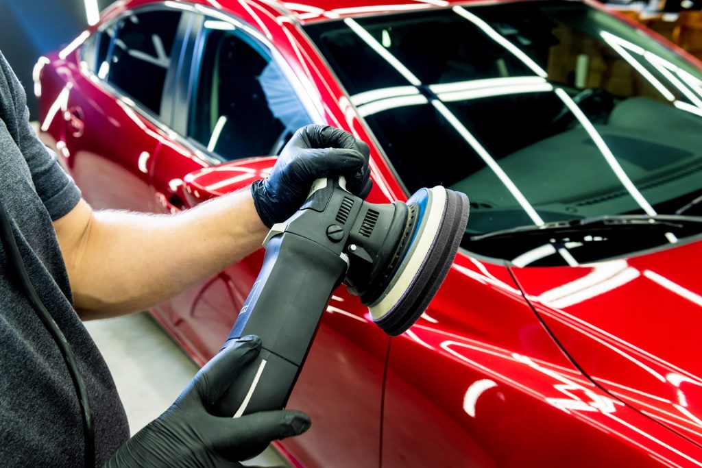a man polishing a red car for paint correction process at luxe detailing pro in anaheim ca